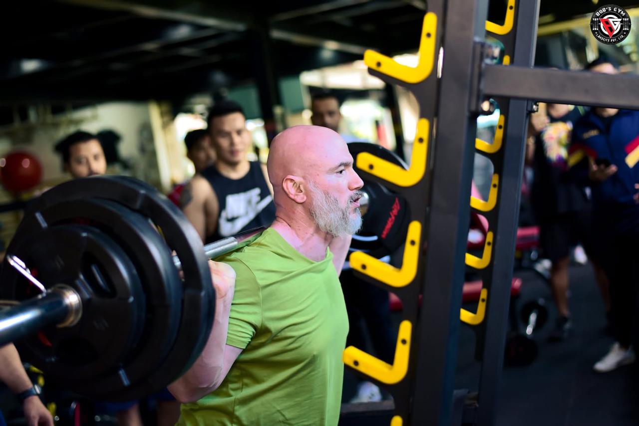 A member performing a weighted squat with coaching support at BobsGym